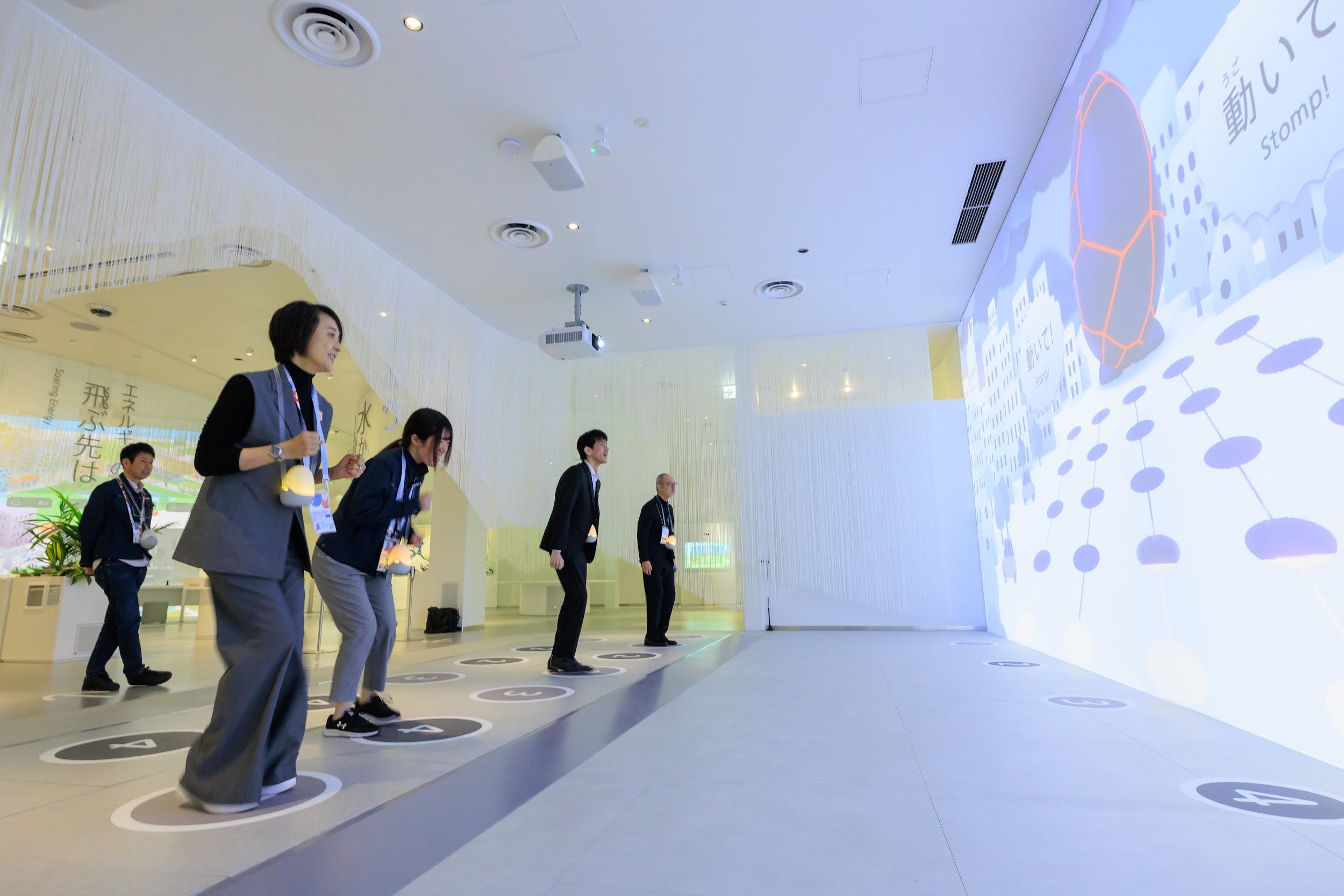 写真)振動力発電コーナーで足踏みをして発電量を競う筆者ら。